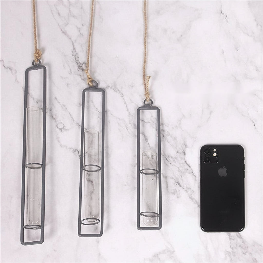 Three hanging glass candle holders on a marble surface with a smartphone for scale.