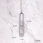 Hanging glass vase with measurements on a marble background