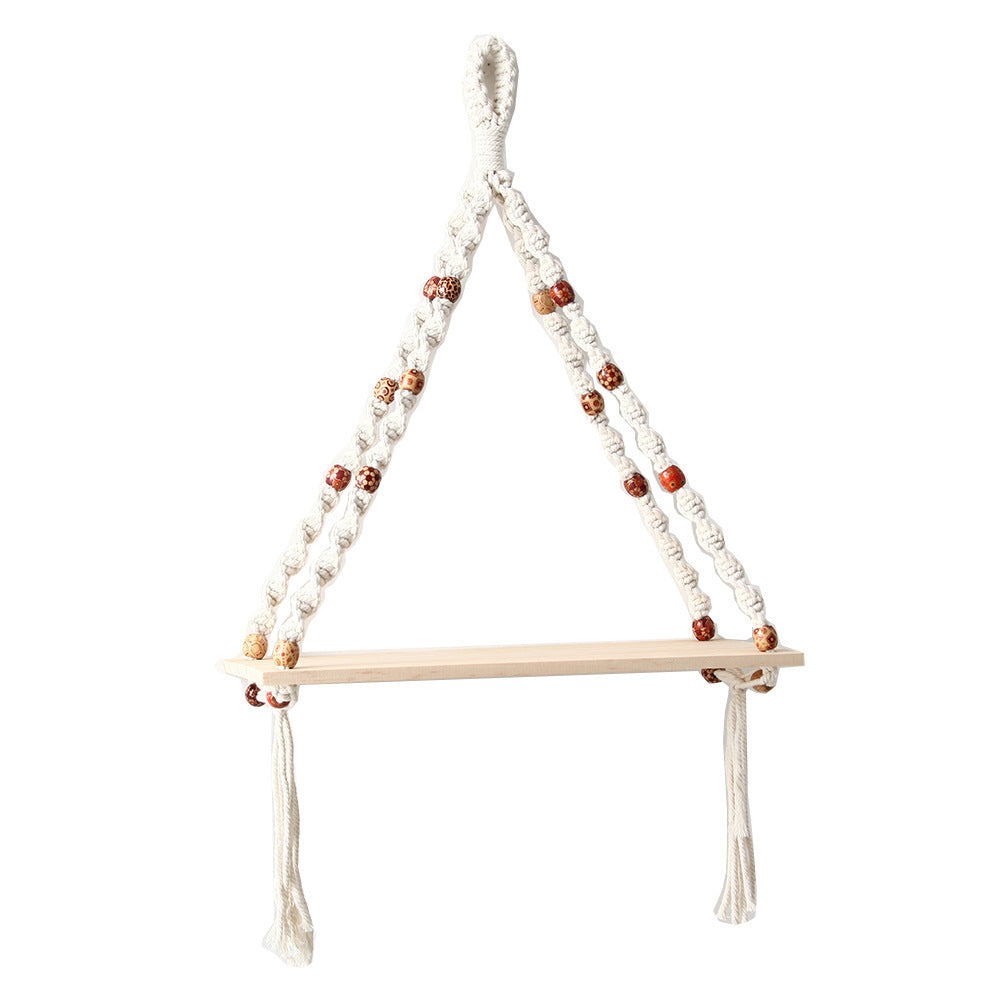 Macrame wall hanging with wooden shelf on a white background