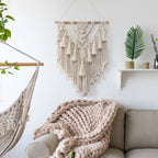 Living room with beige sofa, macrame wall hanging, and plant decor.