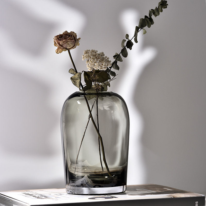 Clear glass vase with dried flowers on a light surface
