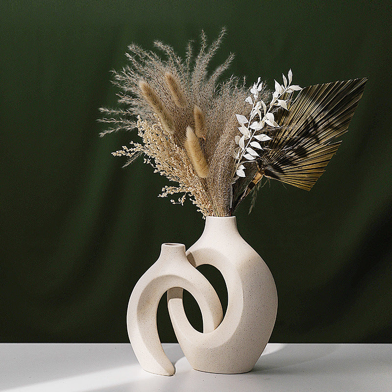 White ceramic vase with a unique spiral design containing dried plants on a dark green background