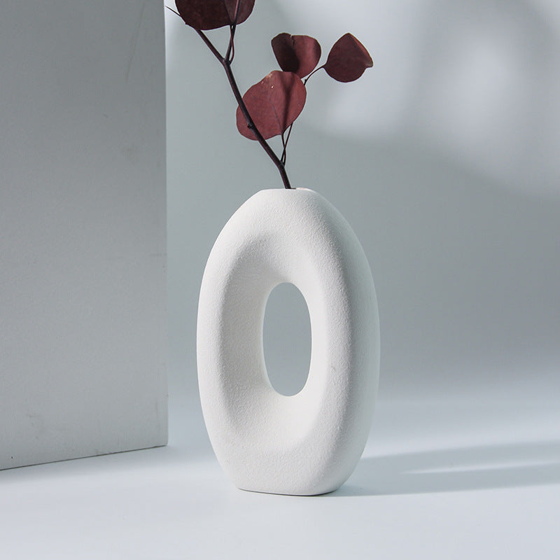 Modern INS-style ceramic vase with an oval opening displayed with dried stems.