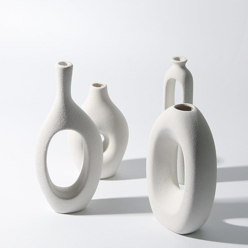 Set of four white ceramic vases with unique designs on a light gray background