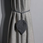 Gray curtain tieback with leaf design on a gray curtain against a gray background