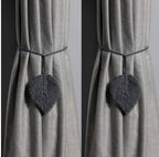 Gray curtains with decorative heart-shaped tiebacks against a plain background
