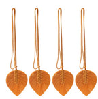 Four orange leaf-shaped macramé decorations with strings on a white background
