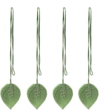 Four green leaf-shaped ornaments with strings on a white background