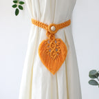 Yellow macrame heart-shaped curtain tieback on a white curtain with a light gray background