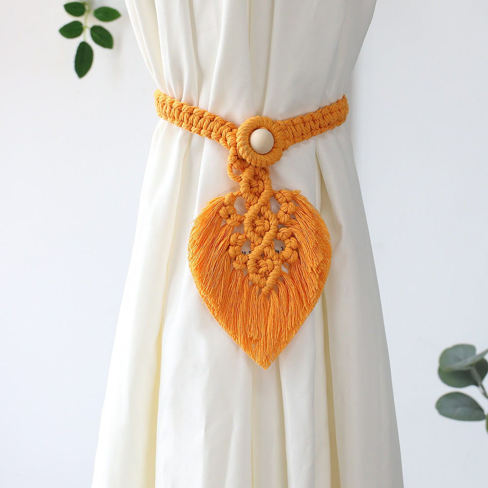 Yellow macrame heart-shaped curtain tieback on a white curtain with a light gray background
