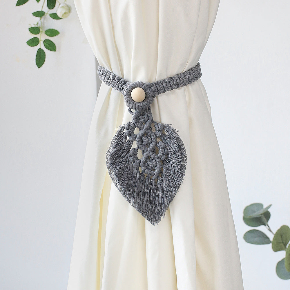 Gray macrame curtain tieback with decorative elements on a white curtain