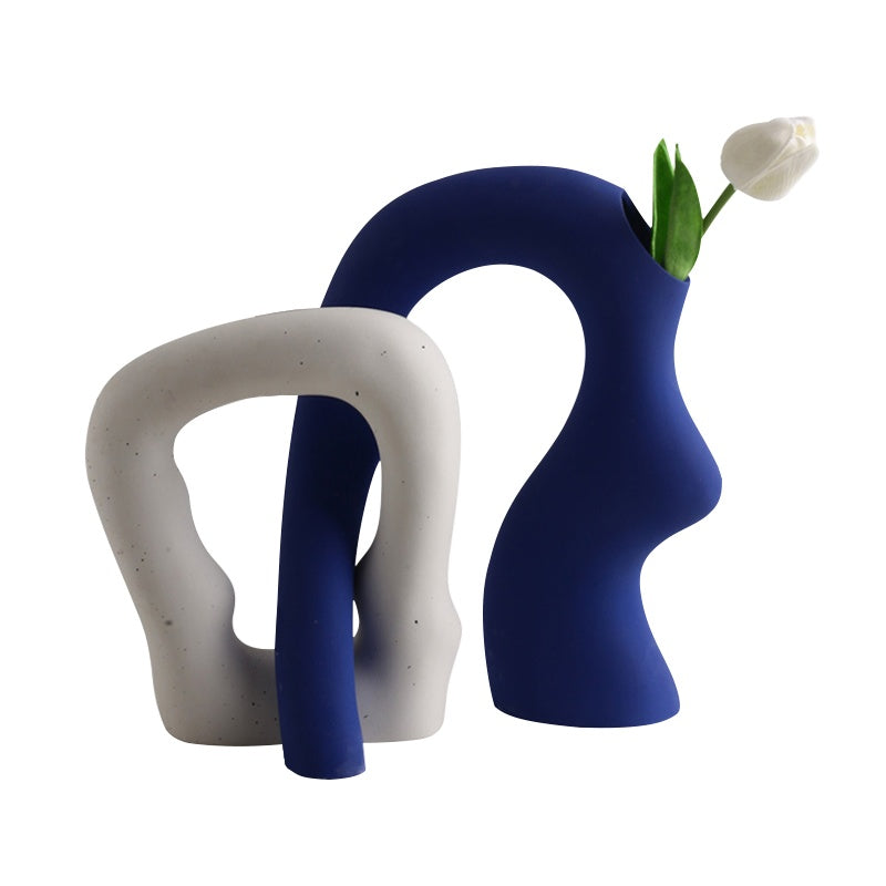 Two modern vases, one white and one blue, with a white tulip on a white background.