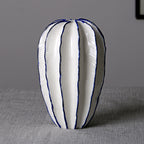 Tall white ceramic vase with vertical sculpted panels and navy edging