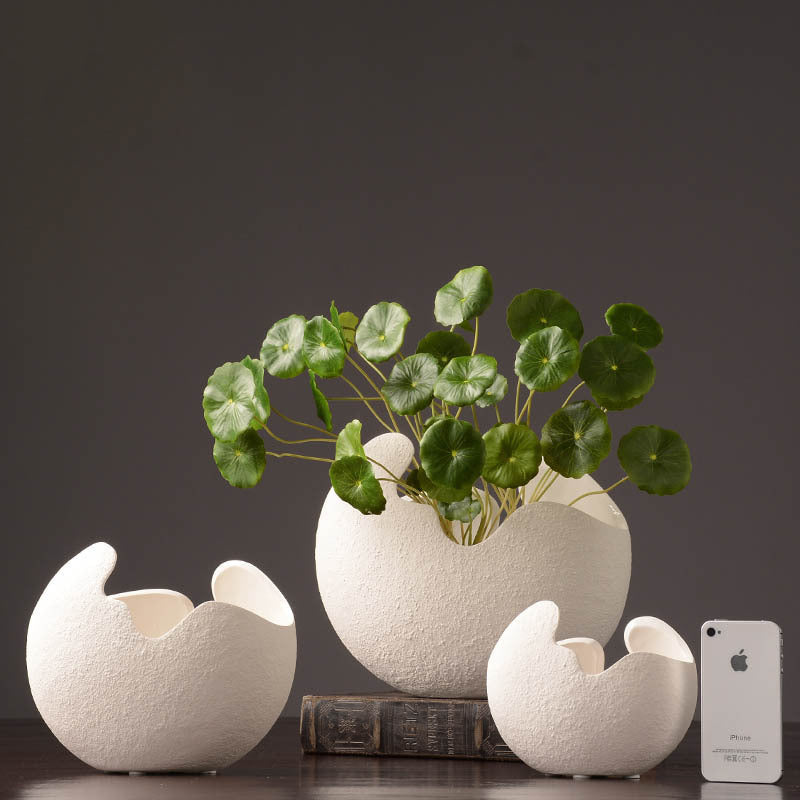 Set of white ceramic egg-shaped vases with a plant on a dark background. Lunara Textured Ceramic Vase Set.