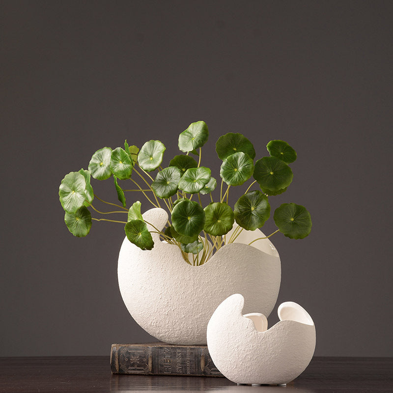 White textured vase with green leaves on a dark background