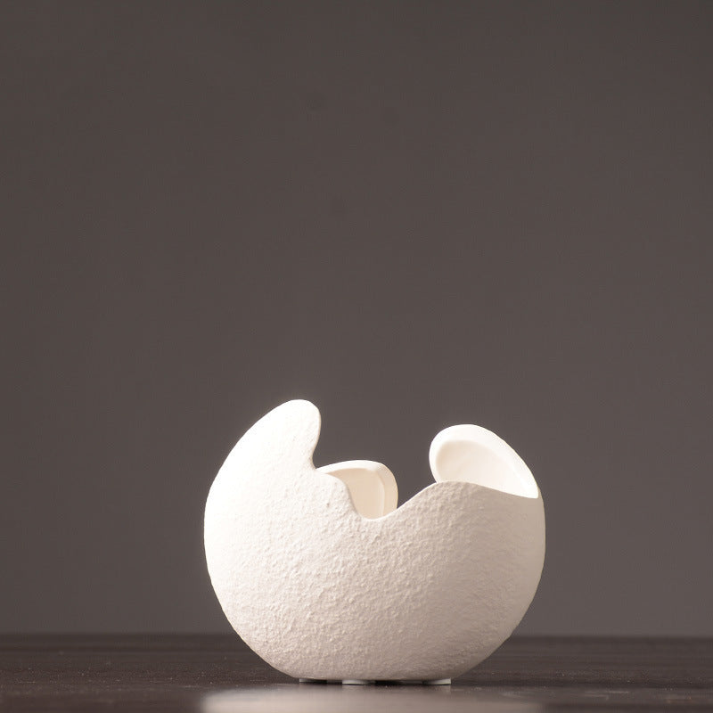 White ceramic egg-shaped object on a dark background.