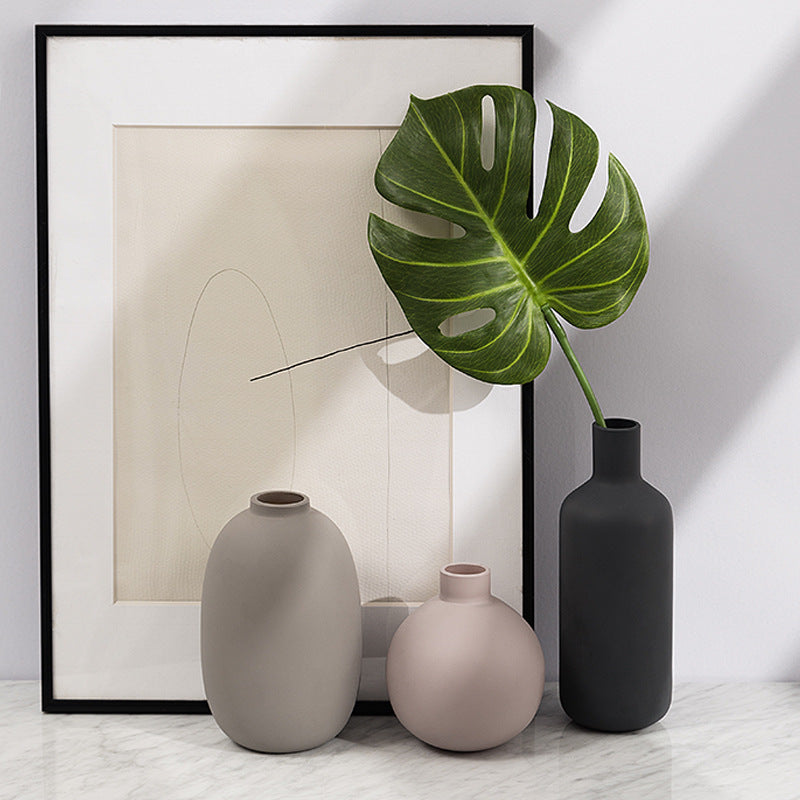 Three vases on a marble surface with a framed abstract artwork in the background. Miora Frosted Glass Ceramic Vase.