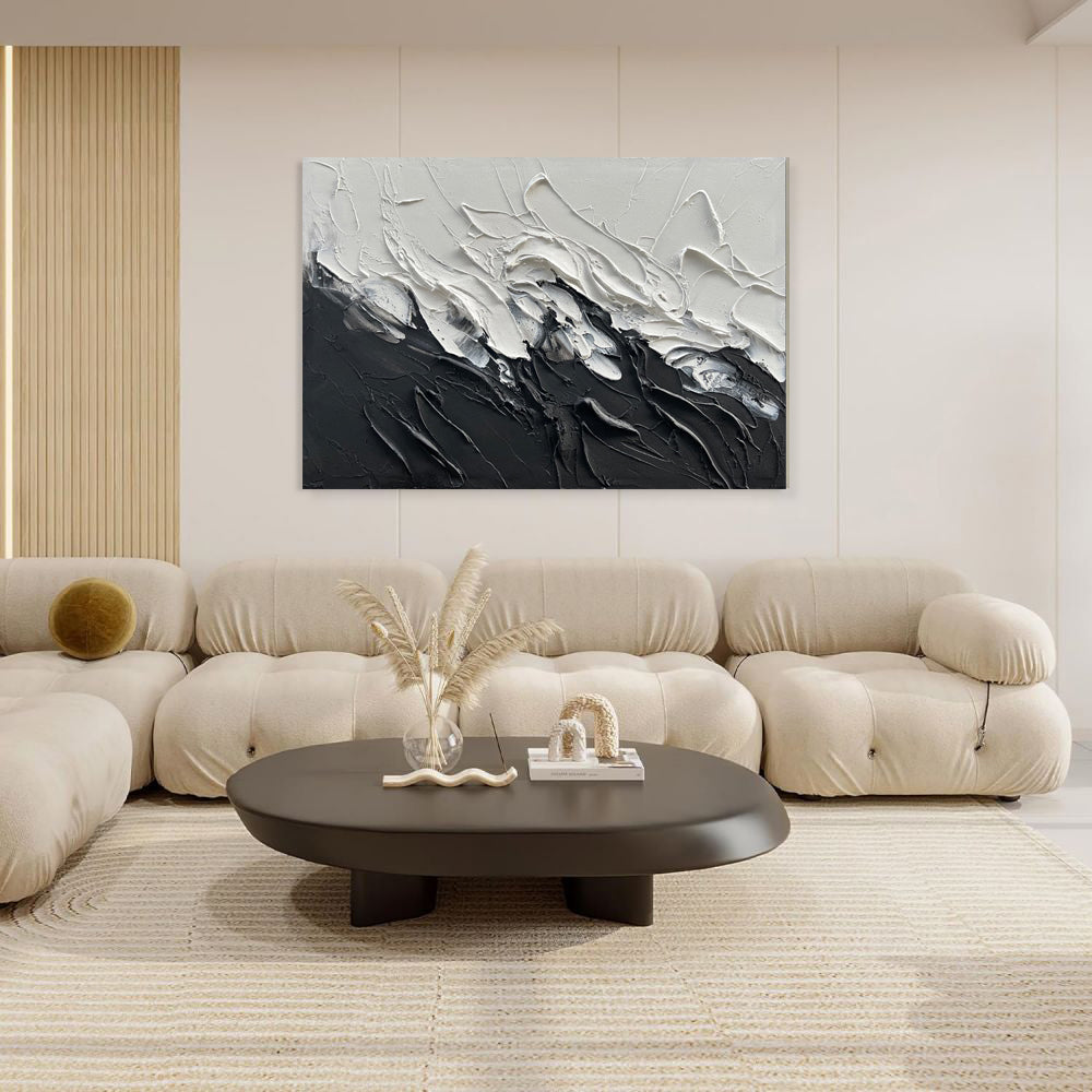 Modern living room with a beige sofa, round coffee table, and abstract black and white painting on the wall.