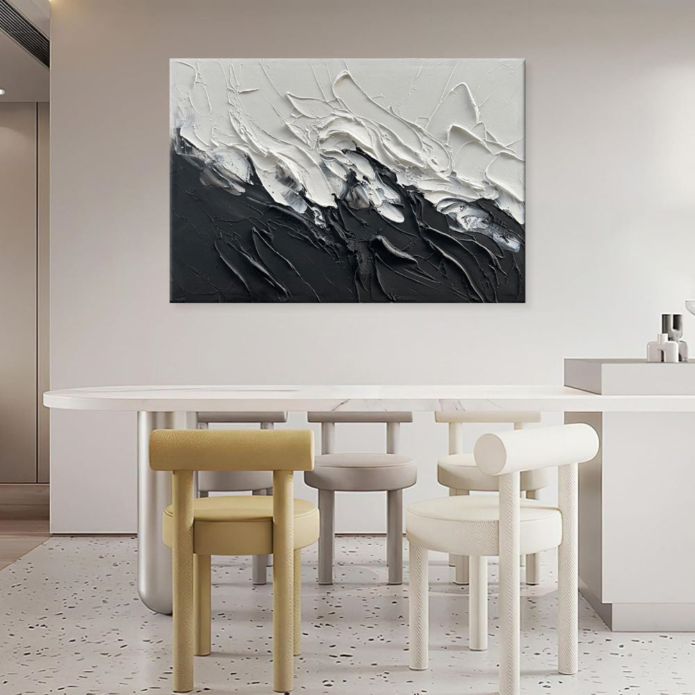 Abstract black and white painting on a wall above a dining table with modern chairs.