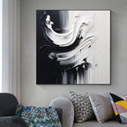 Abstract black and white painting on a wall above a sofa with patterned cushions.