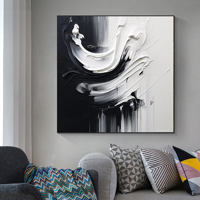 Abstract black and white painting on a wall above a sofa with patterned cushions.