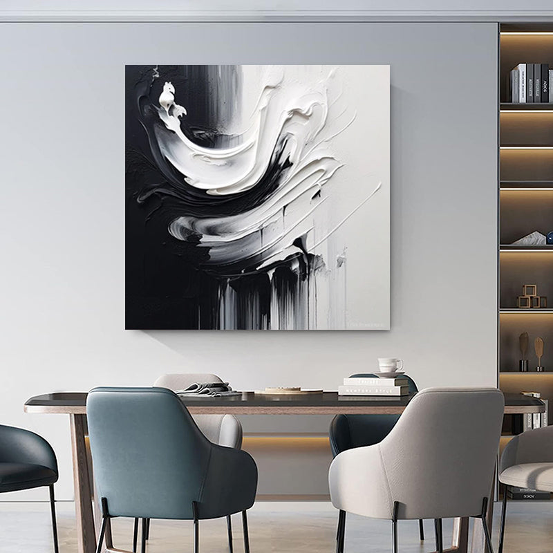 Abstract black and white painting on a wall above a dining table with chairs.