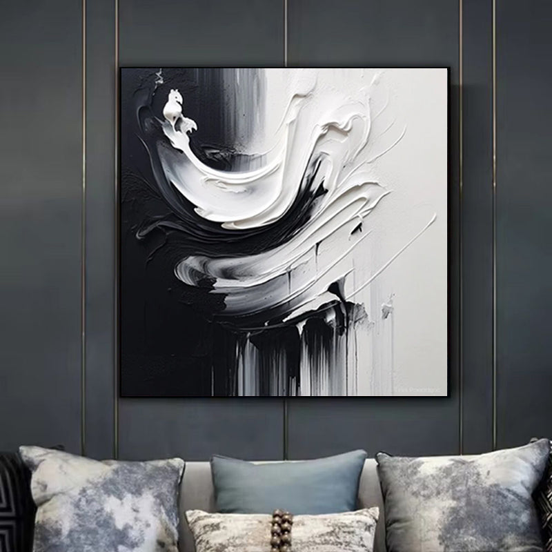 Abstract black and white painting on a wall above a sofa with patterned cushions.