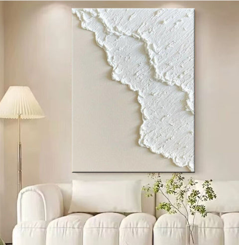 Abstract white artwork on a beige wall above a white sofa.