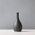Dark gray vase on a white surface with a gray background