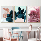 Three floral prints on a wall above a dining table with chairs.