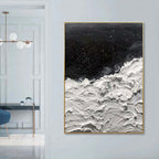 Abstract art piece with black and white textures on a wall in a modern interior setting.