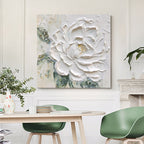 Decorative floral painting on a wall above a dining table with green chairs.