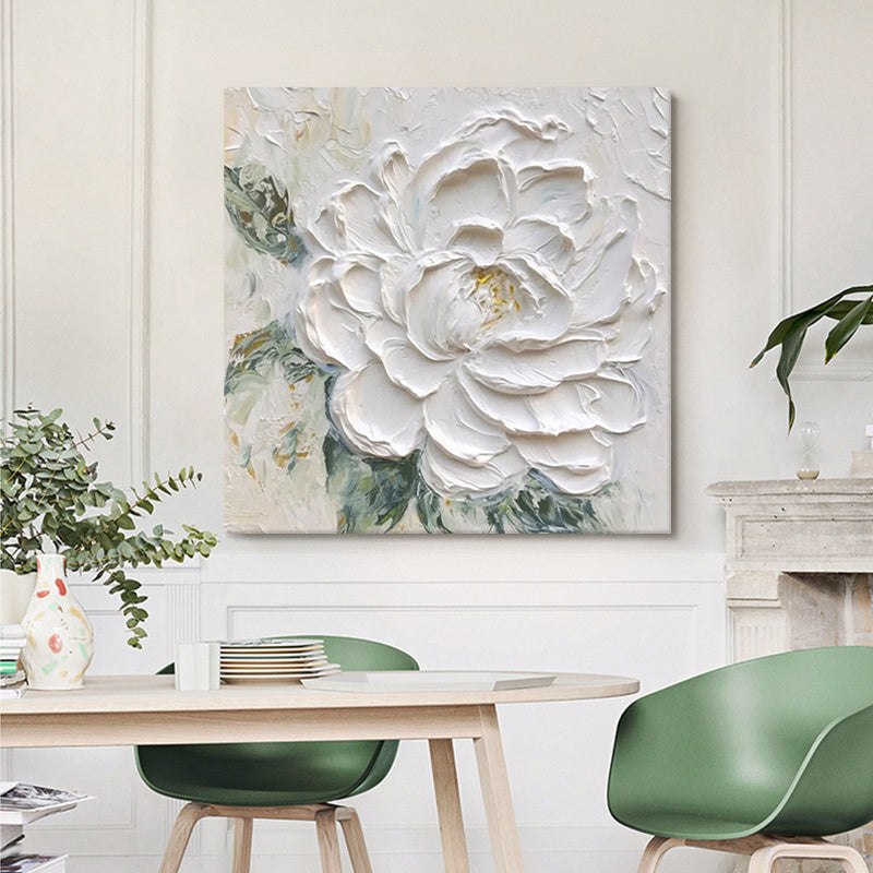 Decorative floral painting on a wall above a dining table with green chairs.