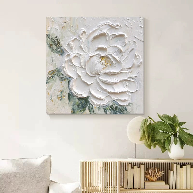 White floral painting on a wall above a white sofa with decorative items.