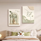 Two framed artworks on a wall above a bed with decorative pillows. Soft Harmony – Cream Line Art Wall Décor