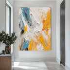 Abstract painting with yellow, blue, and white on a wall in a modern interior setting.