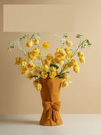 Mustard-colored minimalist floral vase with handcrafted texture and sculptural bow detail