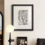 Framed abstract artwork on a wall in a room with a lamp and another framed piece.