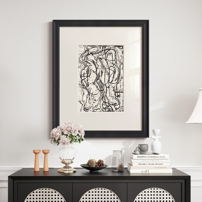 Framed abstract artwork on a wall above a black console table with decorative items.