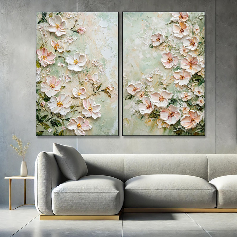 Two floral paintings above a modern gray sofa in a living room setting.