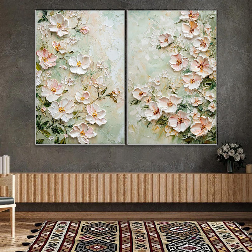 Two floral paintings hanging on a wall above a wooden console table.